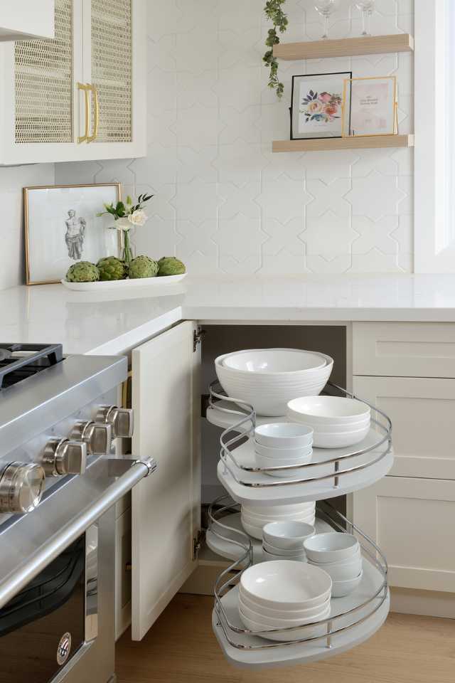 custom built corner shelving for dishware in white designer kitchen with gold accents
