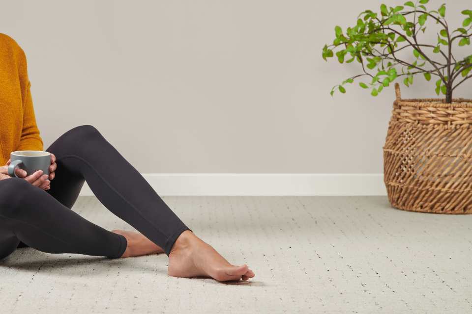 woman sitting on brand new floors in clean home with soft carpet and plant